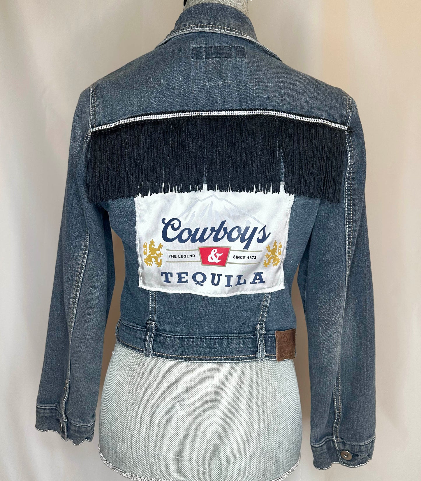Black Fringe "Cowboys & Tequila" Denim Jacket Back Side, featuring black fringe with rhinestone detailing and satin patch