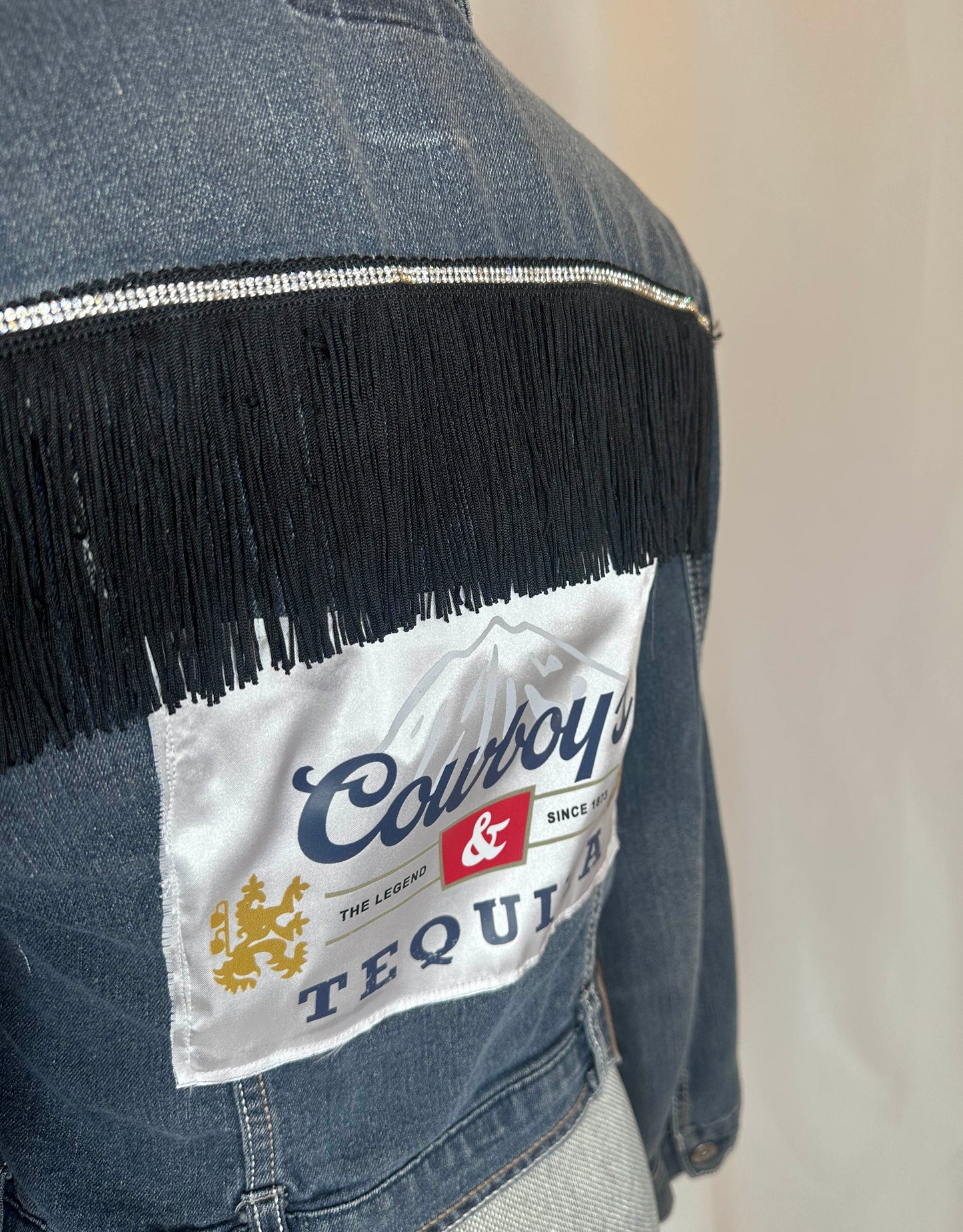 Black Fringe "Cowboys & Tequila" Denim Jacket Back Side, close up featuring black fringe with rhinestone detailing and satin patch.