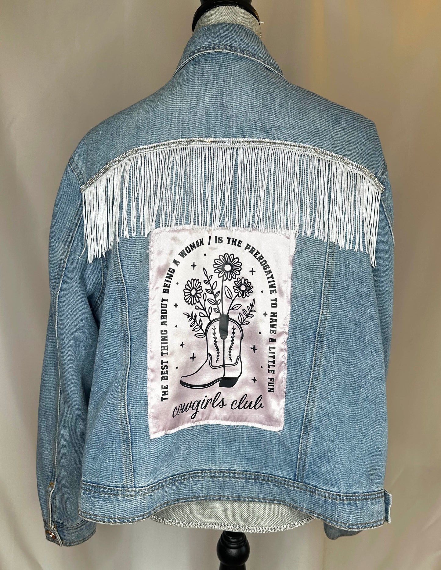 Fringe_Cowgirl_club_Womens_Denim_Jacket_Back_Side featuring natural denim, sequin with white fringe detailing and satin patch.