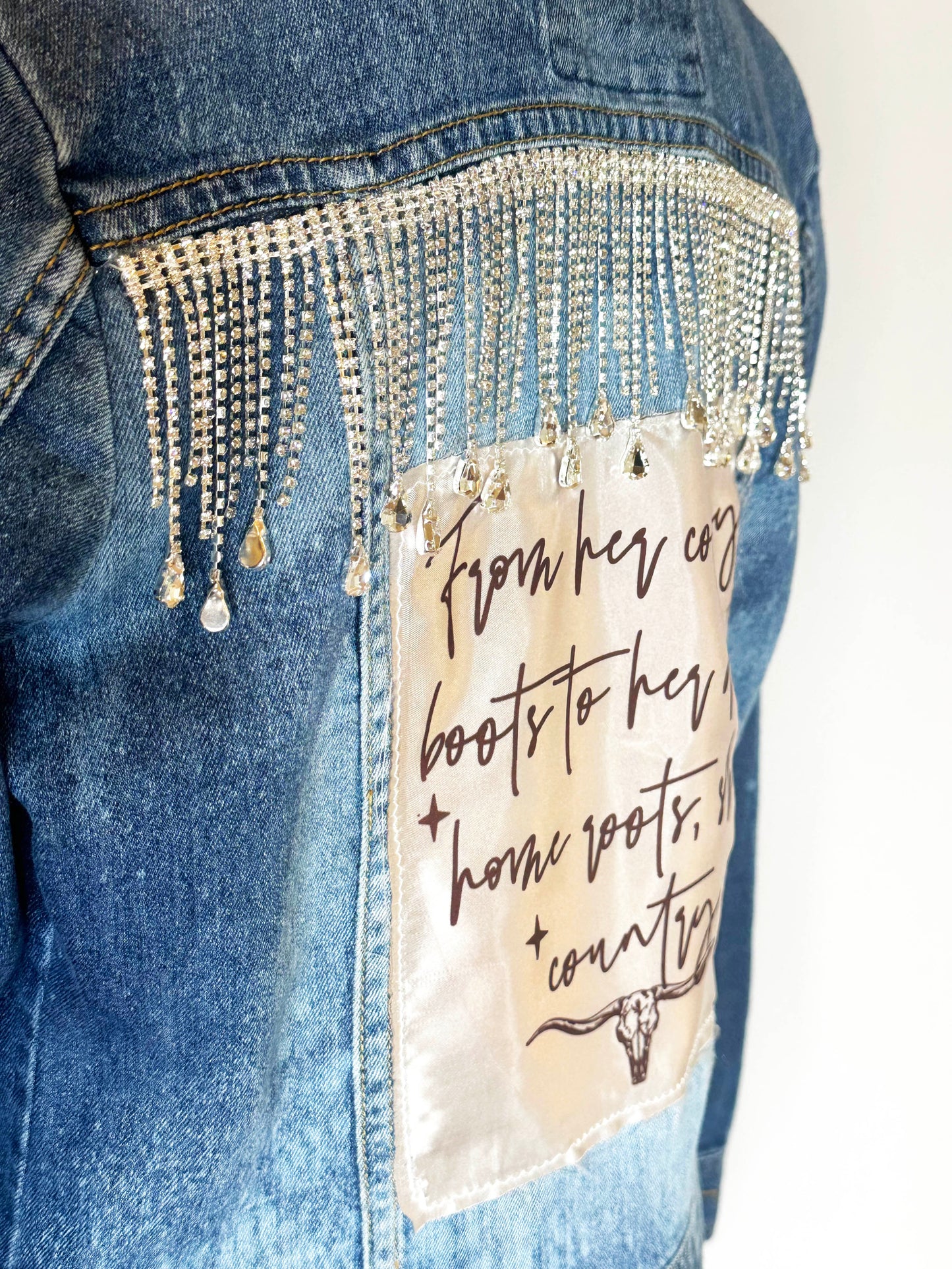 "From her cowboy roots" Womens Denim Jacket Close Up of rhinestone detailing and satin patch.