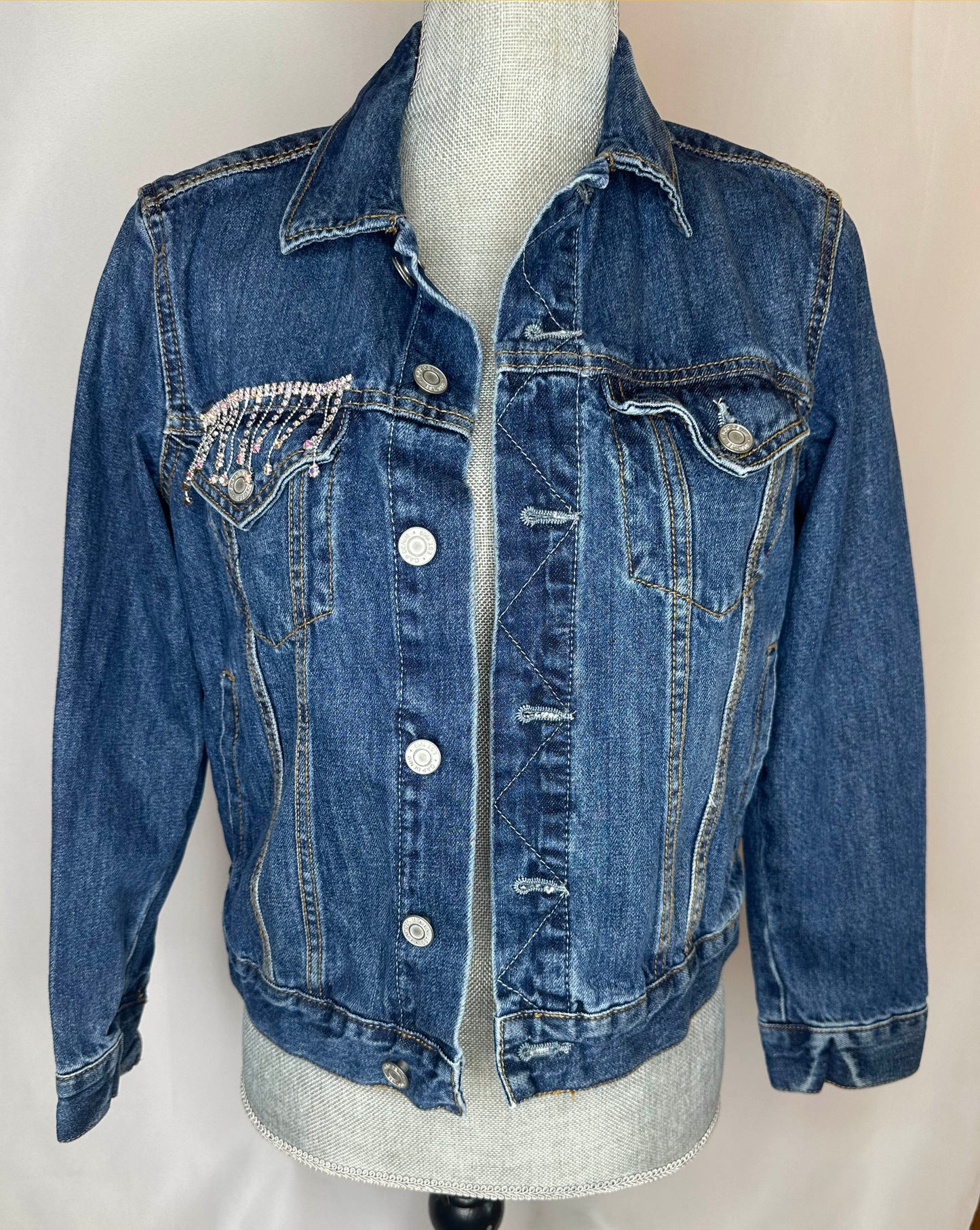 "Howdy" Women's Fringe Denim Jacket Front Side featuring double pocket design, seamless stitching and rhinestone detailing on right side pocket.