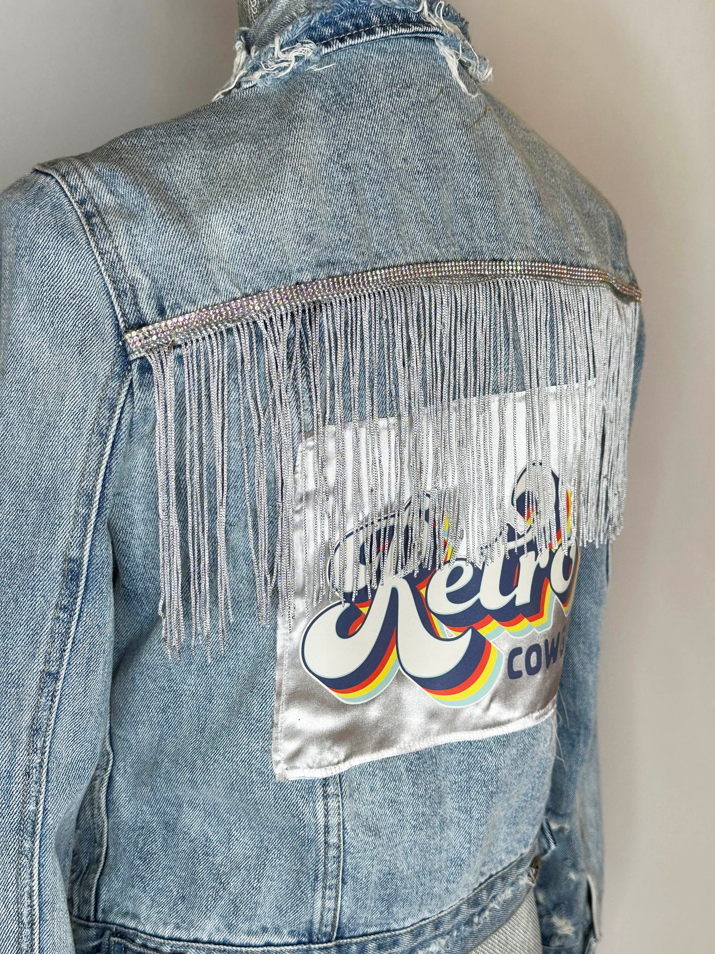 "Retro Cowgirl" Women's Denim jacket Detailing distressed collar, rhinestone fringe back detailing and satin patch.