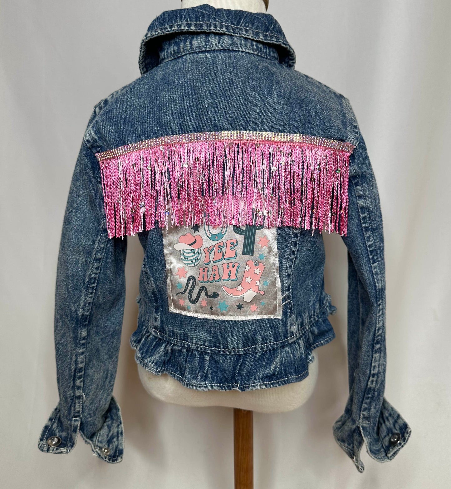 "Yee Haw" Pink Fringe Kids Denim Jacket Back side featuring rhinestone detailing, pink fringe and satin yee-haw patch.
