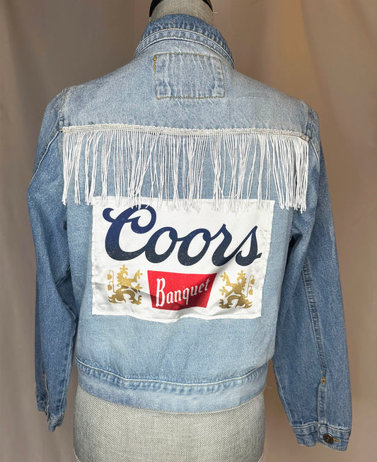 "Coors Rodeo" Women's Fringe Denim Jacket Back Side featuring rhinestone trim with white fringe detailing. 