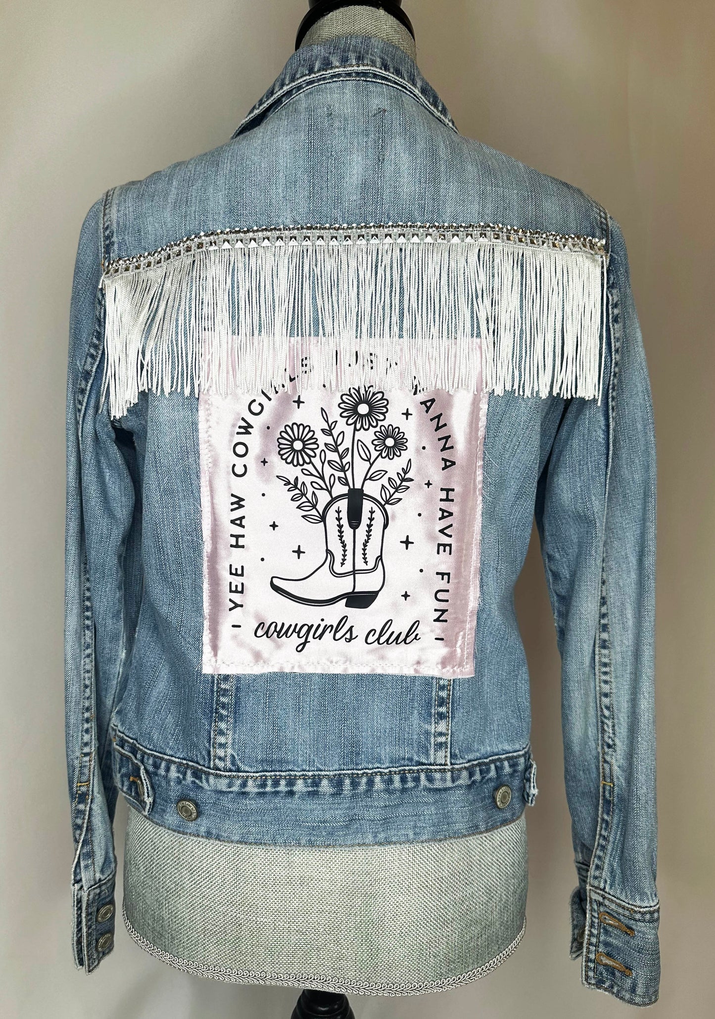 "Cowgirl Club" Fringed Womens Denim Jacket Back Side featuring rhinestone fringe detailing and pink satin "yee haw cow girls just wanna have fun" patch