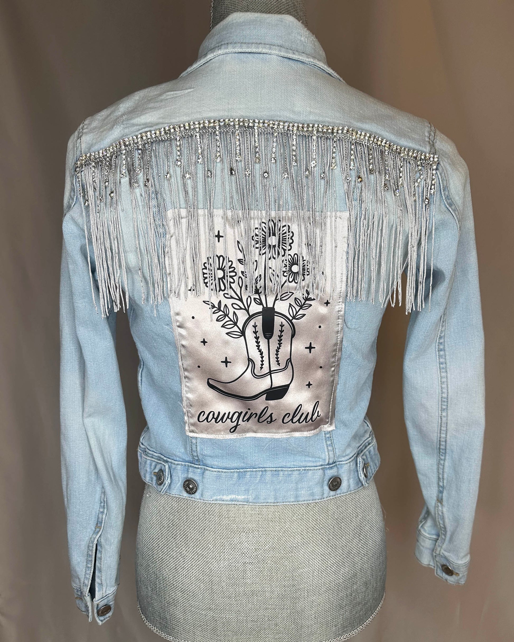 Fringe "Cowgirl club"  Womens Light Denim Jacket Back Side. Silver rhinestone detailing with silver fringe and satin patch.
